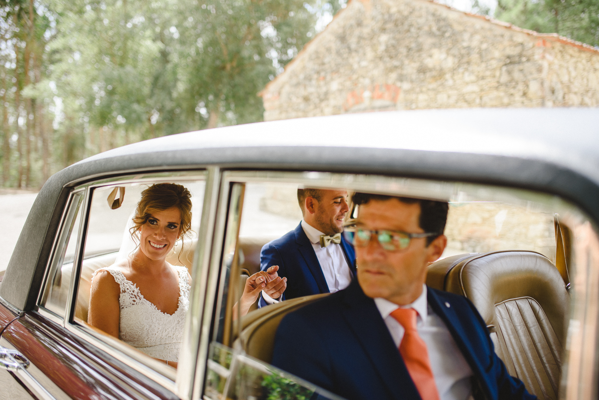 Bride and groom arriving the wedding venue in a classical car holding hands.