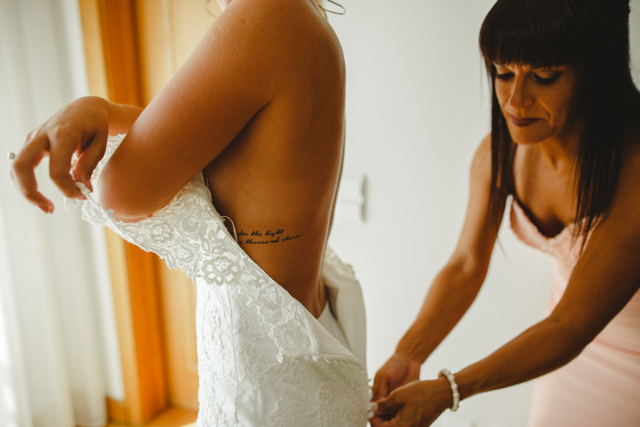 Bride getting dressed with the help of a friend.