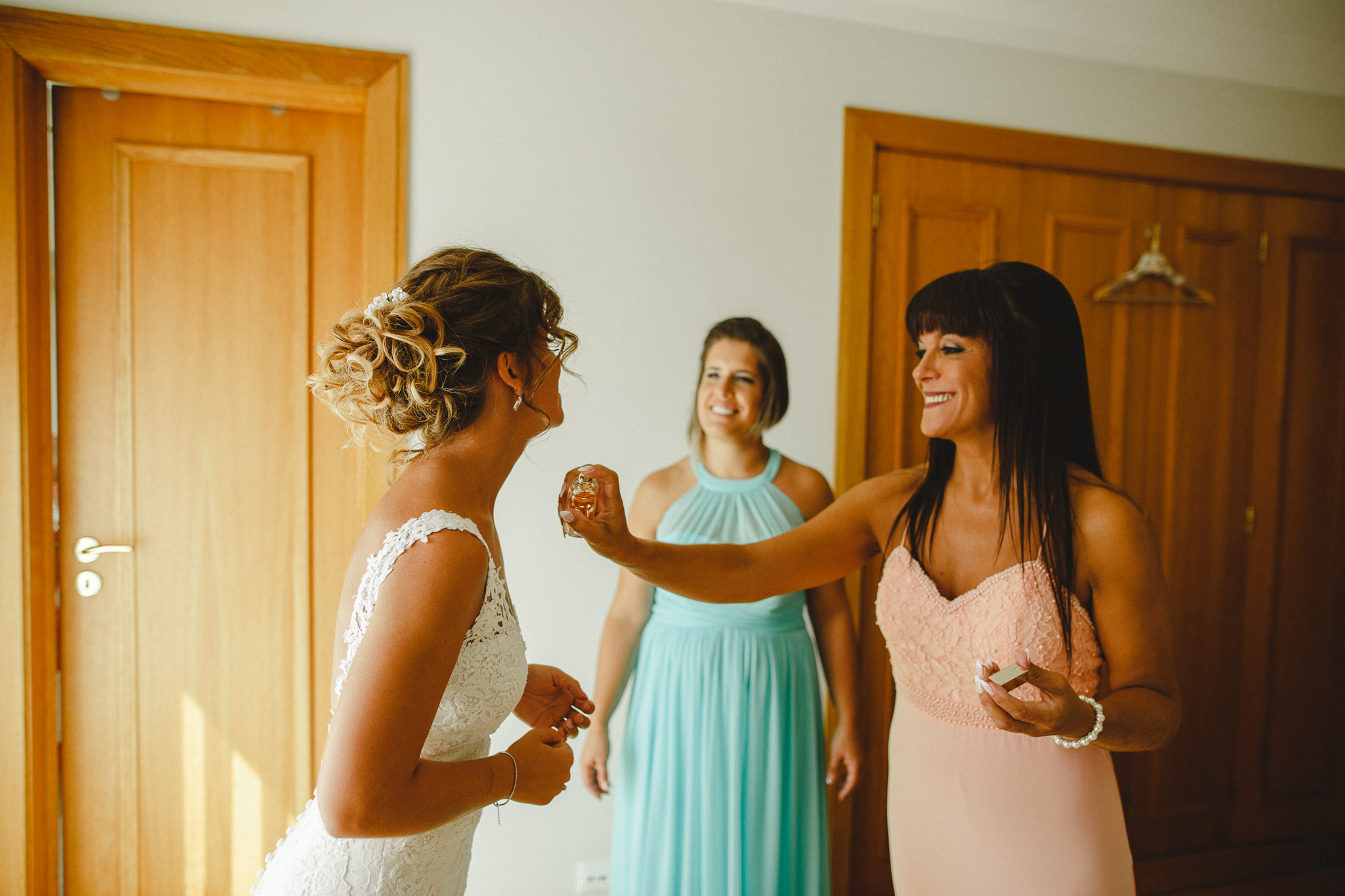 Bride being sprayed with perfume by a friend. 