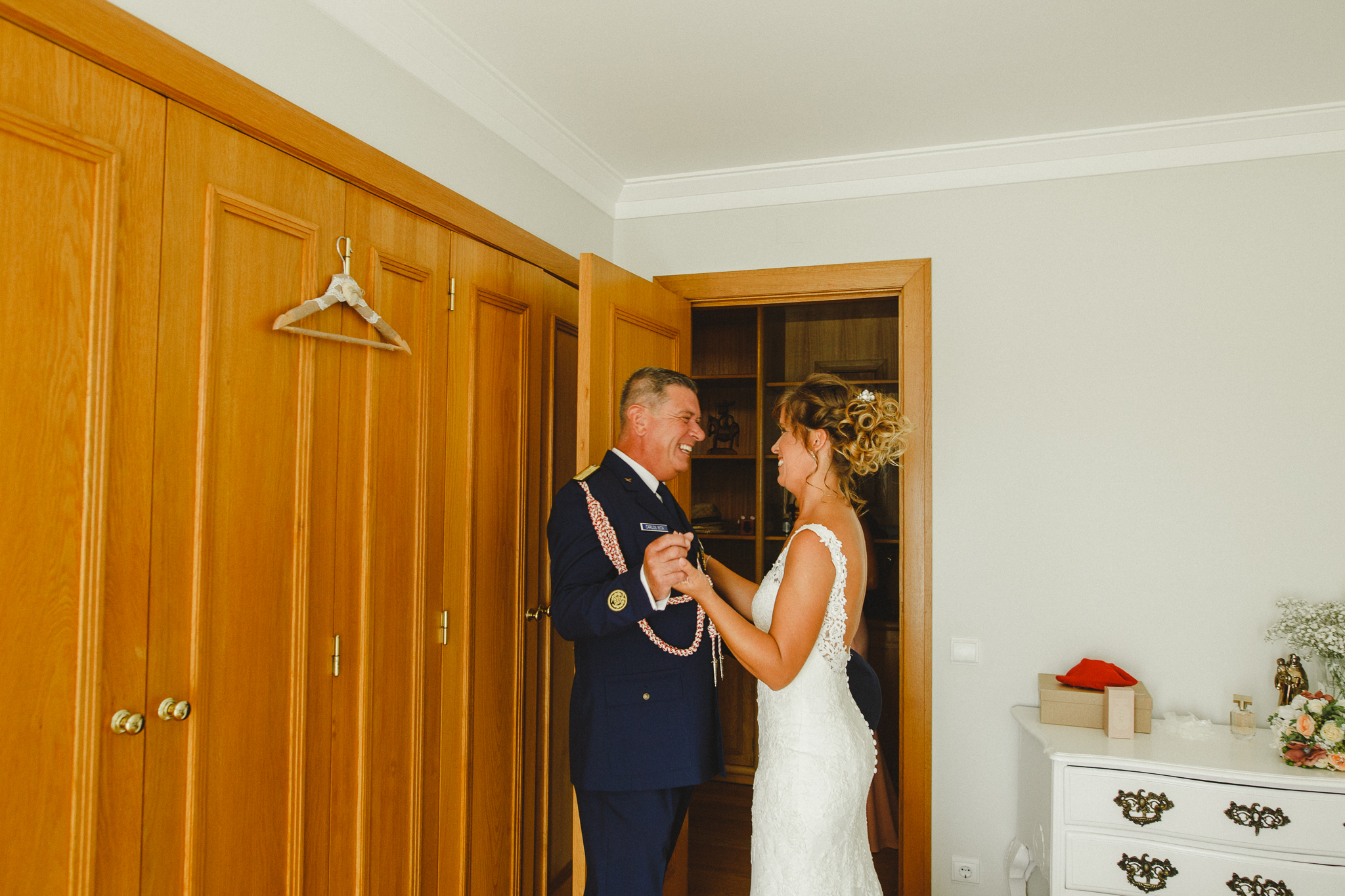 Bride and father of the bride holding hands smiling.