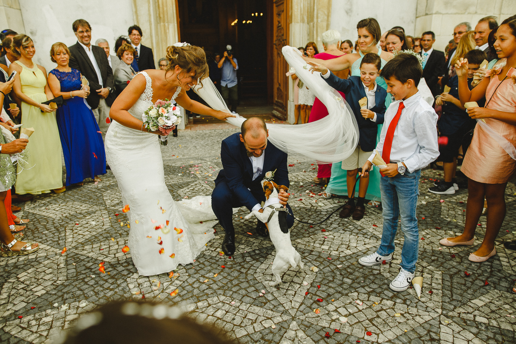 Bride and groom petting their dog after leaving church