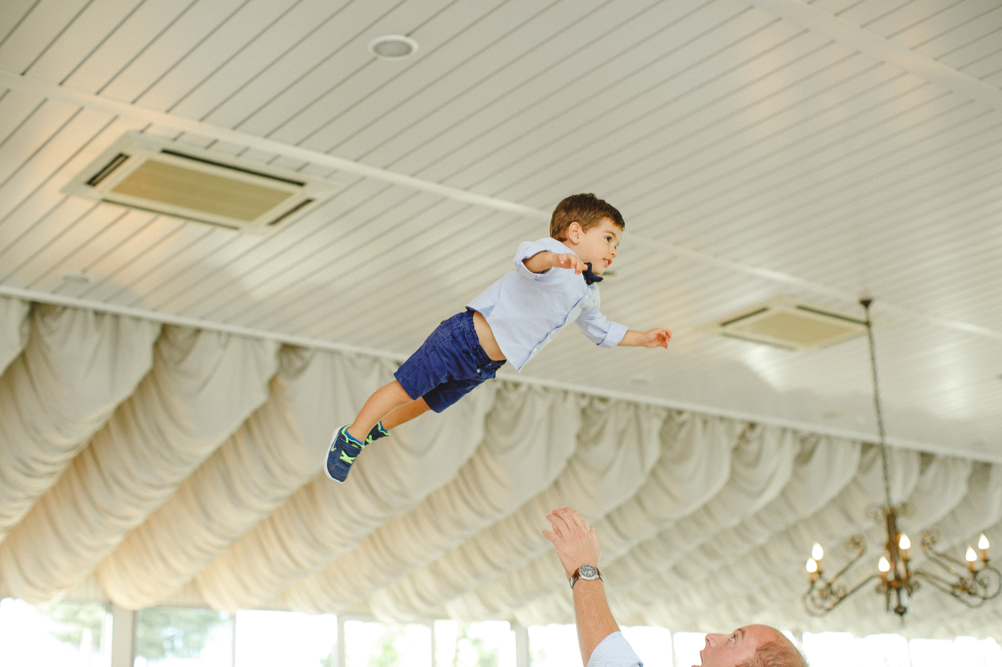 Young kid being thrown up in the air by his father for fun