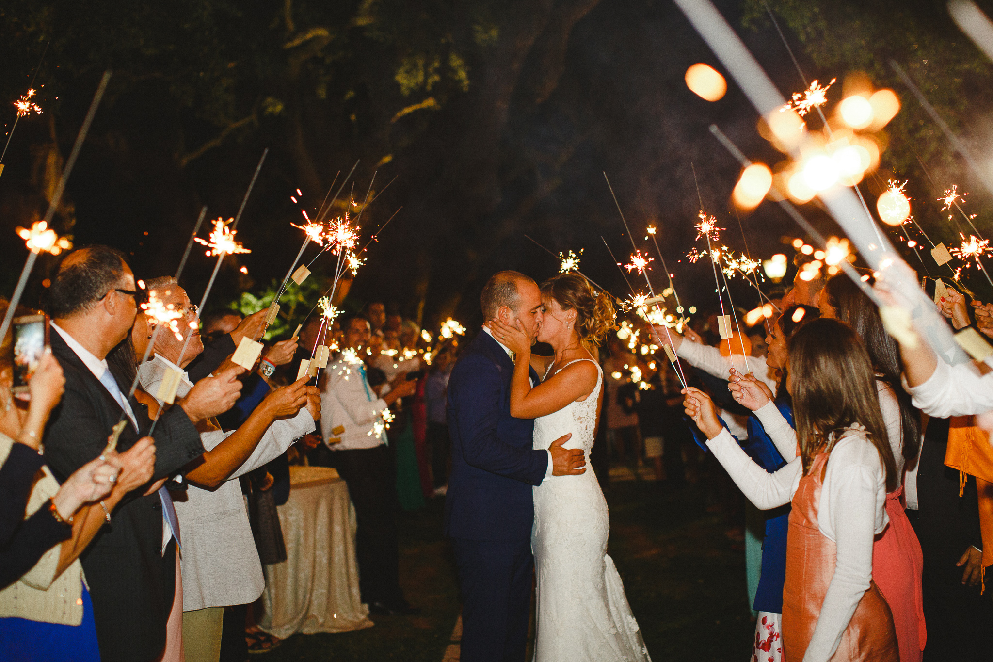 Bride and groom kissing while walking in the middle of guests towards their wedding cake