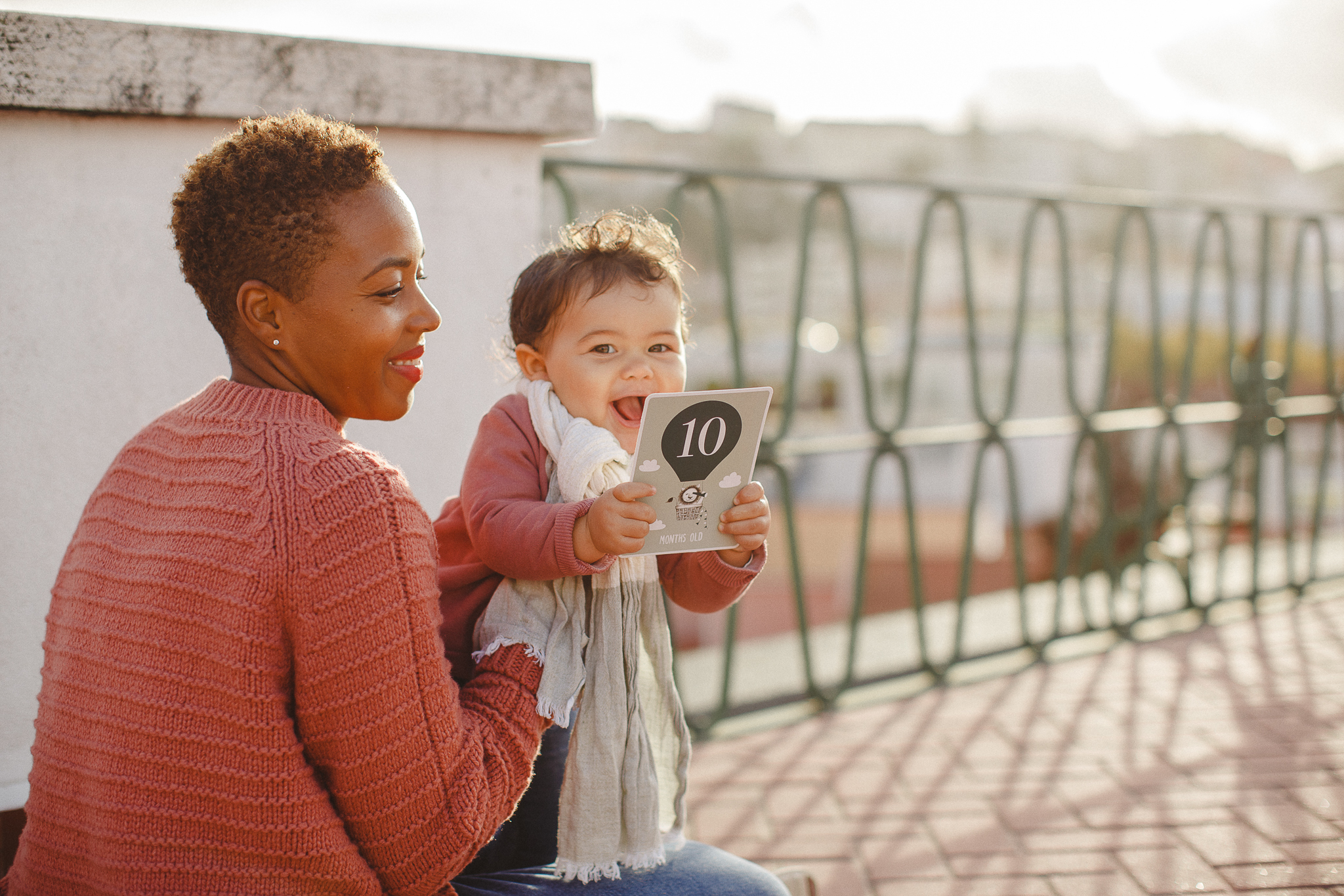 Baby girl smiling holding a 10month-old sign during a family photo shoot in Lisbon with Hello Twiggs. 