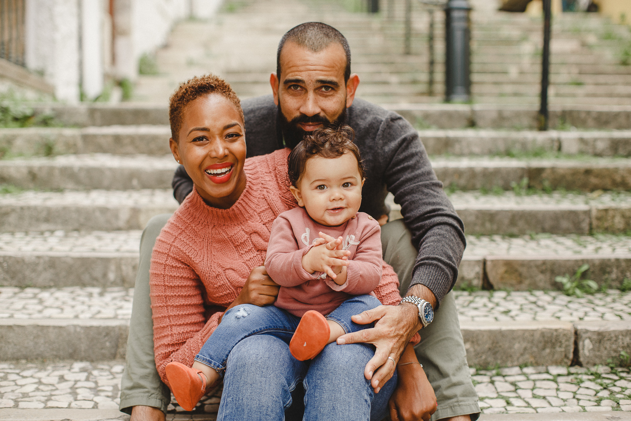 A family sitting on the stairs in Lisbon smiling during a family photo shoot.