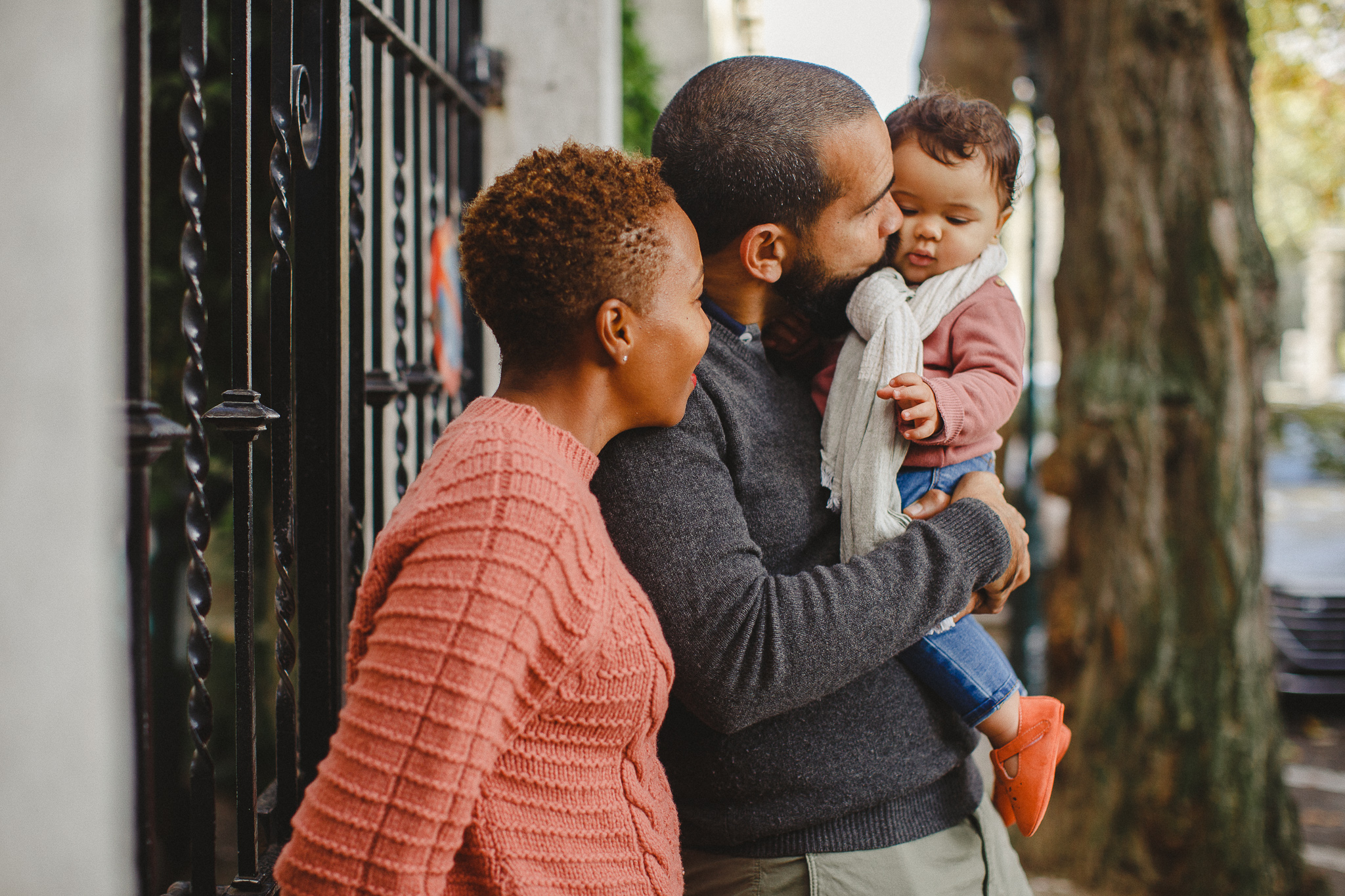 Dad holding his baby daughter and kissing her on the cheeks during a family photo shoot in Lisbon. 