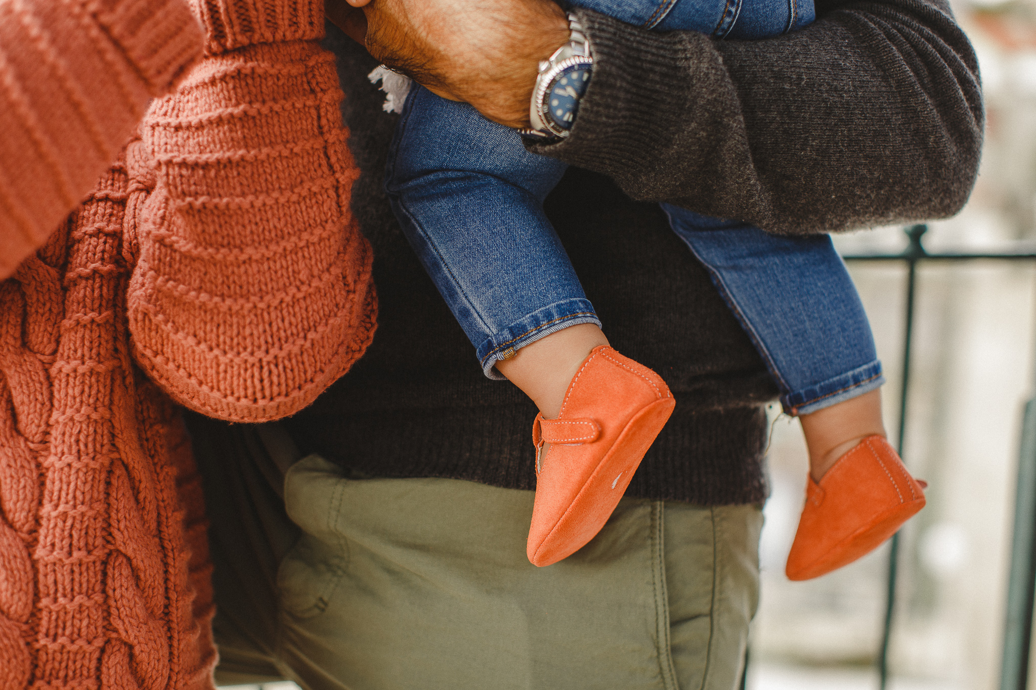 Baby being held by her dad, wearing coral's soft sole shoes. 