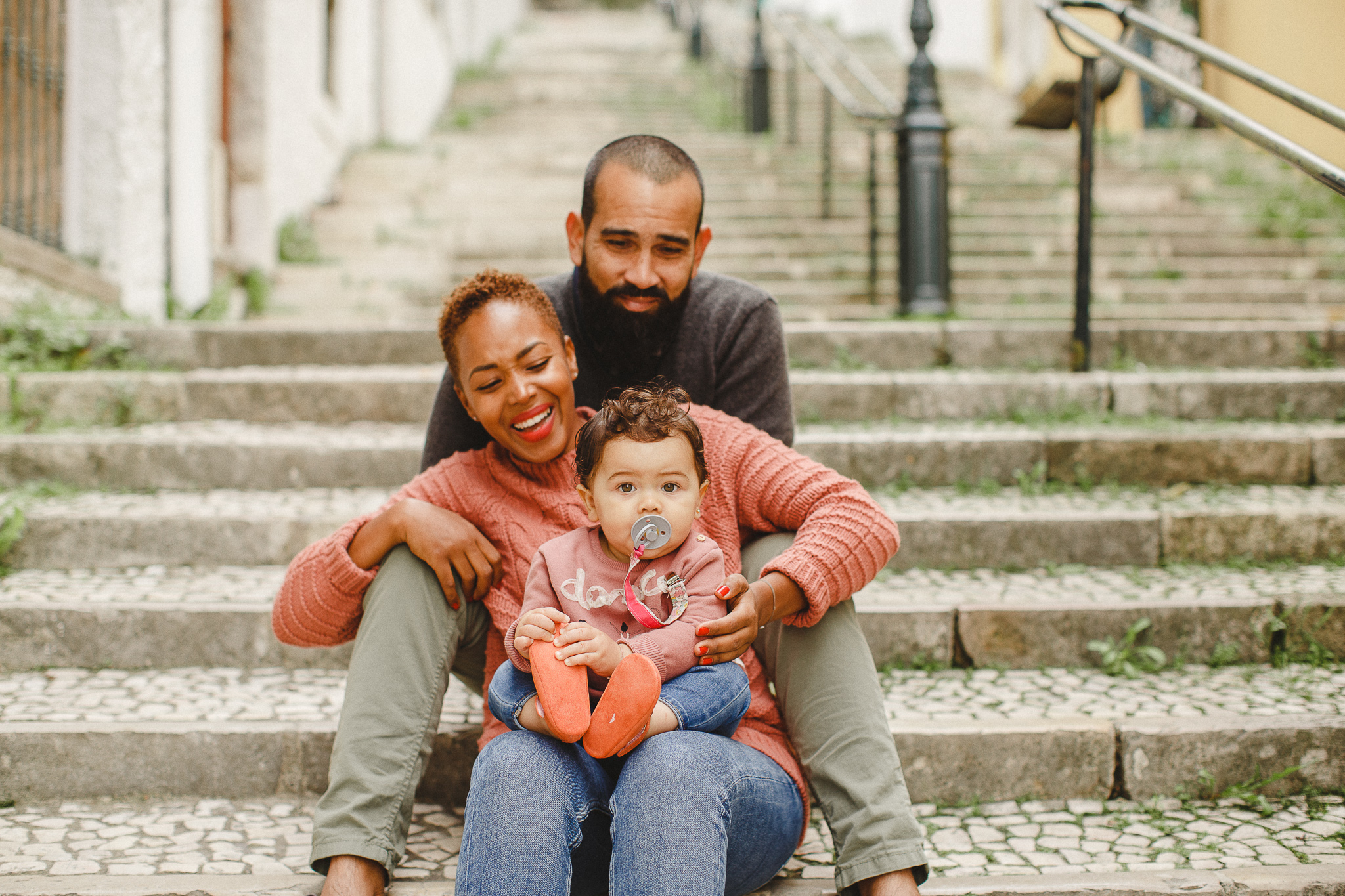 A family sitting on the stairs in Lisbon smiling during a family photo shoot.